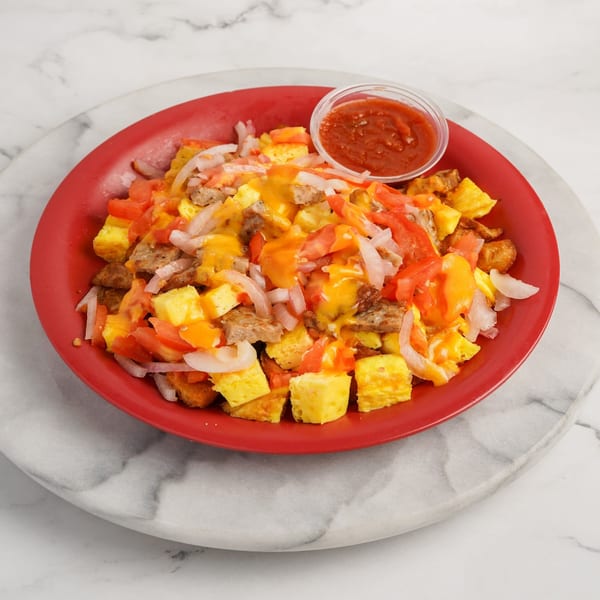 A red plate filled with Bagel Nosh's breakfast scramble, topped with cheese, tomatoes, onions, and salsa.