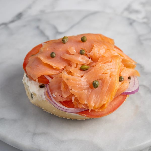 Bagel Nosh bagel with cream cheese, smoked salmon, tomato, red onion, and capers on marble.